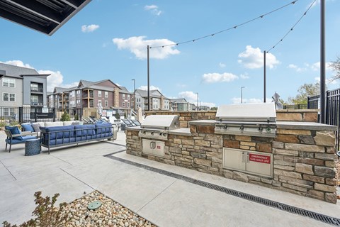 the clubhouse has an outdoor patio with a grill and a seating area at The Quarry Luxury Apartment Homes, Fort Collins